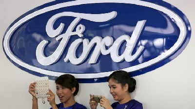 Ford hostesses take pictures at a Ford showroom in Yangon on October 4, 2013
